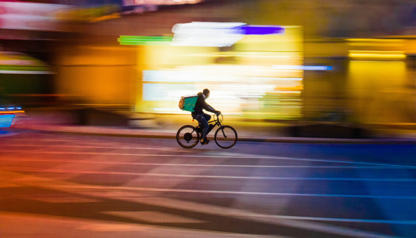 Food delivery cyclist rides fast down the street